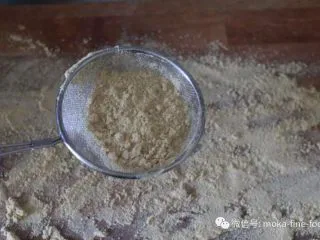 老北京小吃之“驴打滚”,面板上筛一层熟黄豆粉。