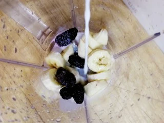 果粒奶昔【香蕉桑葚+香蕉芒果】,把香蕉和桑葚放入榨汁机,倒入牛奶。