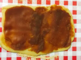 北京小吃·驴打滚,取出莲蓉/豆沙馅。 揉成球状，用擀面杖擀成片状，放到面团上。 注：厚度随个人口味调整。建议不要太厚以免太甜。