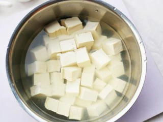 鲜掉眉毛的丝瓜豆腐汤,豆腐切成小块,然后加入淡盐水中浸泡15分钟。(这样一来可以去除豆腥味,二来在炒的时候,可以让豆腐的形状更加完整。)