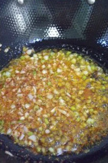 火爆流行街头的龙虾盖浇饭 ,锅中油热放花椒、八角,小火炒香后捞出,再将葱、姜、蒜末放入炒香,最后放辣椒面煸炒至出红油。