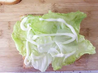 （创意菜）老干妈风味咸鸭蛋酒肠三明治,挤上适量的沙拉酱