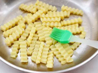 炸锅版狼牙薯条,把冷冻好的土豆条,均匀地涂抹一层薄薄的食用油。