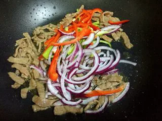 黑椒牛排炒意面,变色立即放入红椒、青椒和洋葱。