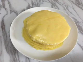 芒果千层蛋糕,将摊好的饼皮放在一个盘子里,摊熟的饼皮这样叠着放也不会粘在一起.