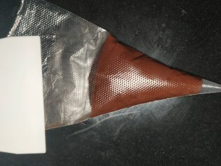 网红夏威夷果仁可可脆脆巧克力片 香港珍妮聪明小熊夏威夷果仁巧克力脆脆,11.把巧克力面糊装入裱花袋，可以利用刮板把裱花袋后端的面糊往裱花袋前端推；