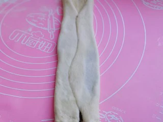 中种豆沙吐司面包,将擀好的长舌状两边向中间对折，用擀面杖轻轻擀长。