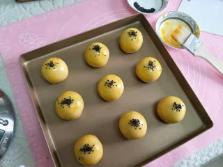 酥掉渣的蛋黄酥，月饼季做起来,所有的制作完后，用毛刷刷蛋黄液，撒少许黑芝麻。