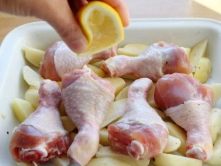 苹果柠香烤鸡腿,将腌了一晚的鸡清洗干净，摆在土豆上，并挤点柠檬汁在鸡腿上。 注：柠檬汁的作用去异味，增香。这里我们没有用姜。 