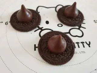 女巫杯子蛋糕,好时巧克力沾少许融化的巧克力,然后沾到奥利奥饼干的中间,晾凉以后做出女巫的帽子,把做好的小花沾到帽子的一边!女巫的帽子就做好了