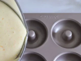橙味甜甜圈蛋糕，在家就可复刻的经典美味,模具提前刷一层轻薄的黄油，蛋糕糊倒入到甜甜圈模具中。倒大约9、10分满。