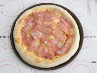 自制培根披萨,将培根均匀的铺在烤好的饼底上。