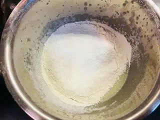 可可波纹戚风蛋糕,待表面没有油花,容器中液体略显浓稠后,完成乳化,筛入低粉与玉米淀粉。这里请将低粉和玉米淀粉事先混合。