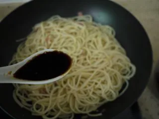 培根芝士意大利面,然后加一勺酱油,把意大利面翻炒均匀。如果发现面条在翻炒过程中太干,可以加点煮面水,因为煮面水里含有淀粉,不仅可以给面增加一些汤汁,也可以增加酱汁的浓稠度。