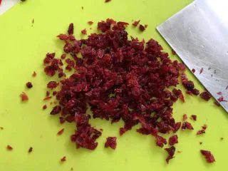 牛奶炼乳蔓越莓软欧,把蔓越莓用温水浸泡一会,用厨房纸巾拭干水分,用刀切碎。