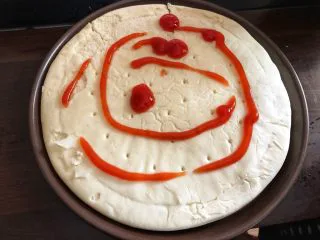 蔬菜火腿披萨,饼胚放在披萨盘里(有些披萨盘要事先刷点油)，上面挤一些番茄酱。