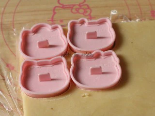 kitty奶酪饼干,取出面团,剪开表面的保鲜膜,把学厨Kitty的饼干压模先压出外形轮毂,把五官的压模在面粉里粘一下再压出Kitty一家的五官(萌萌哒)然后抽掉模具