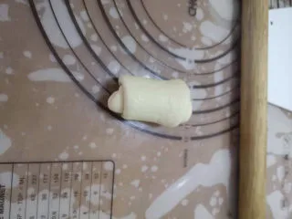 儿时的味道～脆皮蜂蜜小面包,松弛好的面团，按扁擀成牛舌状，自上而下的卷起，将收口捏紧。