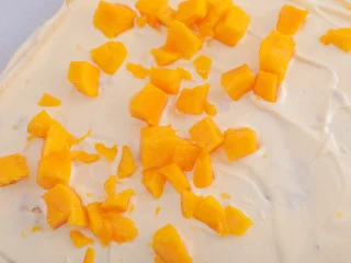 3款像云朵般柔软的瑞士卷,每一口都让人沦陷!,在蛋糕表面抹上奶油,铺上芒果丁。(内馅可少放,放太多卷的时候可能会挤出来哦~