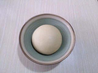 红豆日式咖啡面包卷,将面团取出盖上保鲜膜进行发酵。