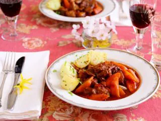 #食二星座#法式红酒炖牛肉 Boeuf Bourguignon,标准的西餐摆桌，西餐盘，刀叉，餐巾纸，红酒，纯净水，还有鲜花。