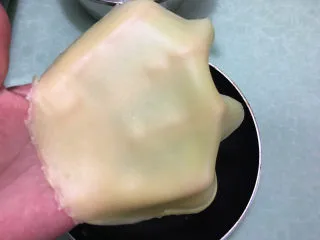 芒果千层蛋糕,摊熟后待饼皮温热了取下来.(有个快速将锅降温的方法:可以备一个比平底锅稍大的盆,里面放上凉水,等饼皮摊好后把平底锅底部放在盆里的凉水上）