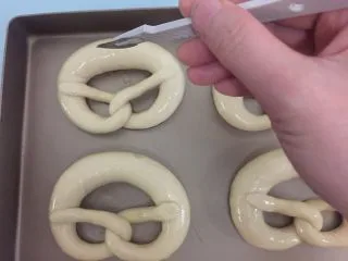 德国碱水面包普雷结,沥干水放在烤盘上,烤箱预热195度10分钟,粗处用刀片割口