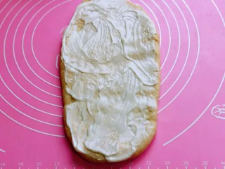 沙拉火腿面包卷,取一款面团，用擀面杖擀长舌状，涂抹上沙拉酱。