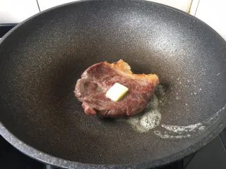 红酒黑胡椒牛排,煎另外一面时放入黄油,中火煎3分钟,然后沿锅边烹入红酒。