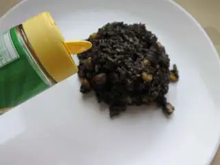 煎南美虾球配意式墨汁海鲜烩饭,烩饭盛入盘中，撒芝士粉，点缀香菜碎