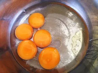 黑芝麻戚风蛋糕,蛋黄中加入玉米油和牛奶搅拌均匀