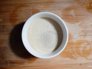 奶香葡萄干小面包（电饭锅版）,在牛奶中倒入4g酵母粉，并用筷子搅拌至融化。