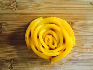 芒果香蕉奶昔,将芒果薄片小心的紧密的围在一起。小片的卷起来做花心，依次从小片到大片的紧密围在一起，成一朵玫瑰花型。