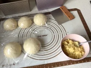 北海道款椰蓉吐司,面团取出，用手按压排气，均分2份，滚圆，盖保鲜膜松弛20分钟。椰蓉馅调好备用 我每次都是做双份，另三个面团是做原味吐司的。 