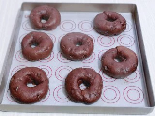 懒人必做~巧克力贝果,将贝果放在垫有油纸的烤盘上淋干。