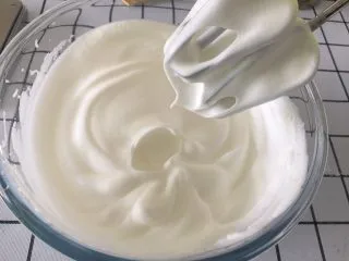 戚风杯子蛋糕,蛋清分两次加入白糖打发好，这里要说明的是装蛋清的容器和打蛋头一定要擦干水分，一滴水或油也不可以有。 打发到提起打蛋器头时出现小竖钩即可，切记不要打发过硬，否则烤出来的蛋糕容易开裂。 