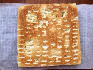 香葱肉松面包卷,倒扣在油纸上，切掉四边不太整齐的边角，用刀在卷起的一边横着划两刀，但是一定不要划透。这样卷的时候就不会开裂了。 