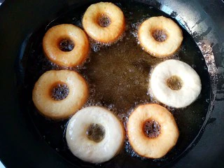 巧克力甜甜圈,锅中宽油,烧至七八成热(温度在180°C左右),将二次醒发后的甜甜圈饼坯下油锅。炸至一面上色后翻面。