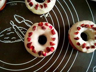 巧克力甜甜圈,蔓越莓根据需要切小块,小玫瑰把花瓣取下来。在巧克力未干时,将蔓越莓和小玫瑰花瓣装饰在上面。