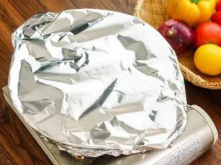 西班牙海鲜饭,倒入白酒搅拌，散上腊肠，带酒气稍微挥发倒入高汤，至完全没过米，加适量盐，转小火煮10分钟，至汤汁收干，铺上各种海鲜，轻压使海鲜半埋在饭中，撒上胡椒，撒上青豆，盖上铝箔纸闷煮15分钟，让米吸汁。