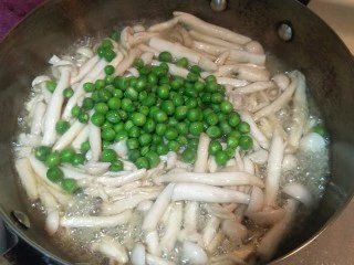 健康低卡香煎鲈鱼,继续把刚刚煮好的小豌豆放入锅中。菇会炒出水分。