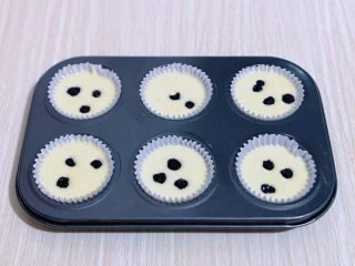 新手入门级～蓝莓椰蓉马芬蛋糕,再把做好的蛋糕液倒入纸托中，每个纸托里再放上几颗蓝莓，轻轻震动模具，将气泡震出。