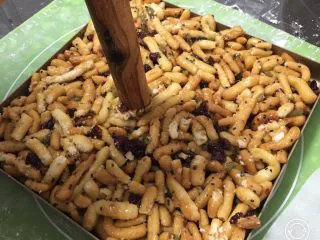 蔓越梅沙琪玛,完成后倒入金盘,用擀面杖压紧。