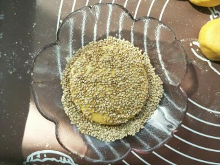 南瓜糯米夹心饼,不用擀，用手轻轻按压即可，按压成一个小饼。（不要按压的太扁，我按的有点太扁了，）然后两面都黏上芝麻。做好后可以油炸，可以用电饼铛煎熟。可以烤箱烤。我今天做的无油健康版，烤的。