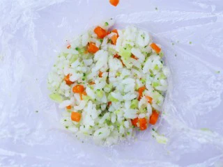 西兰花肉松芝士饭团,取一块保鲜膜，将饭团放入保鲜膜中。