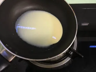 芒果千层蛋糕,根据自己平底锅的大小舀适量面糊,拿到燃气灶上,开小火,平底锅在火上转着将面糊摊匀.