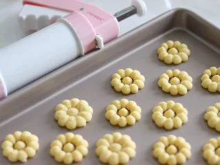 醇香酥脆的曲奇饼干(曲奇枪版),冬日温暖小零食,挤到烤盘上即可,这里需要注意一下,尽量直接挤到烤盘上,如果垫油纸的话,会导致曲奇花离模失败,油布的话相对好些,如果油布也不好操作的话,就尽量挤到烤盘上吧。