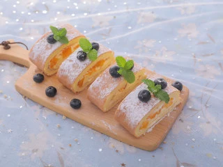 3款像云朵般柔软的瑞士卷,每一口都让人沦陷!,冷藏好后拿出来撒上糖霜,切成蛋糕卷,用蓝莓和薄荷装饰,芒果瑞士卷就做好啦,开吃吧~