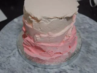 巧克力淋面蛋糕,剩余的淡奶油加入细砂糖和一滴红色素打发,取1/3抹在最上面层,剩余的再加入一点点红色素混匀,取出抹在蛋糕边上