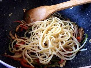 西餐之黑椒鸡丝意大利面,辣椒变软后关火，将意大利面放入锅中搅拌，每根面粘上黑胡椒汁即可